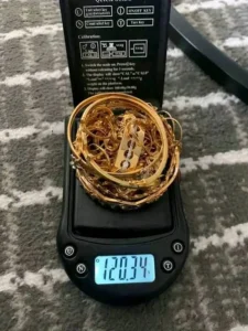 Tumpukan perhiasan emas di atas timbangan digital menunjukkan 120,34 gram