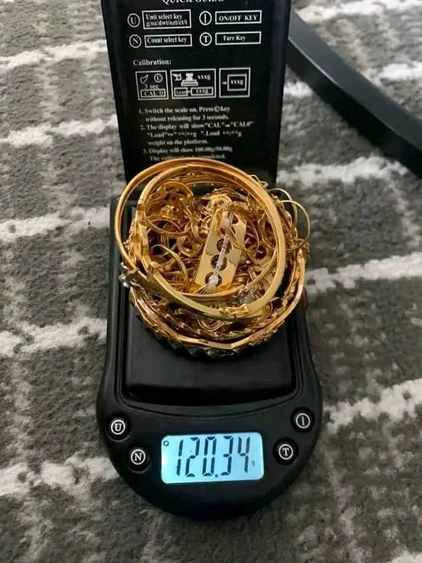 Tumpukan perhiasan emas di atas timbangan digital menunjukkan 120,34 gram
