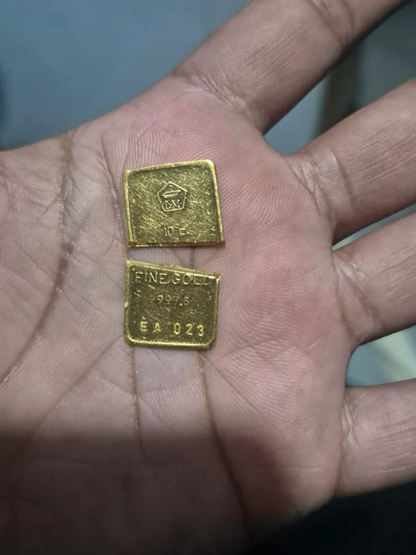 Dua potongan logam mulia bertanda Fine Gold 999.9 dan 10 gram di telapak tangan
